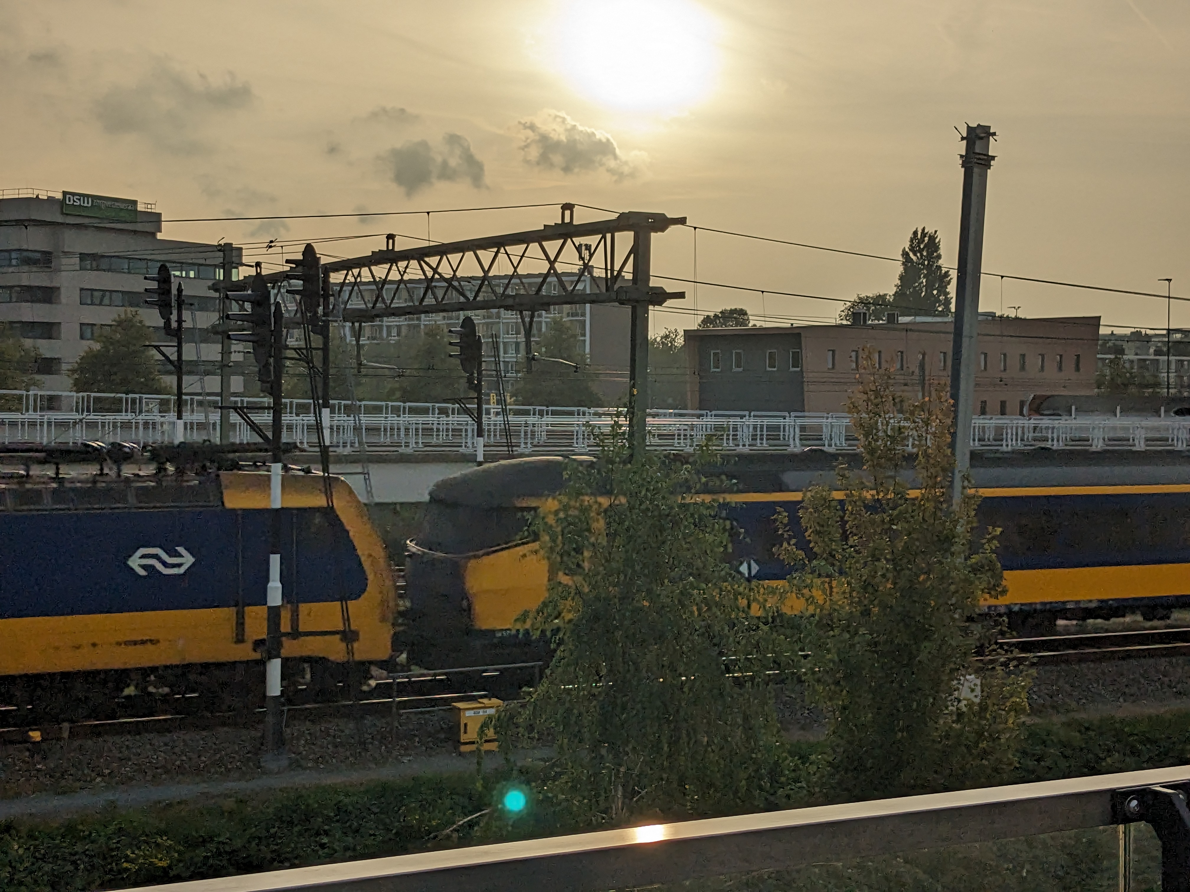 Photo of a Traxx locomotive in NS livery pulling a set of ICR carriages with the sun low on the horizon.