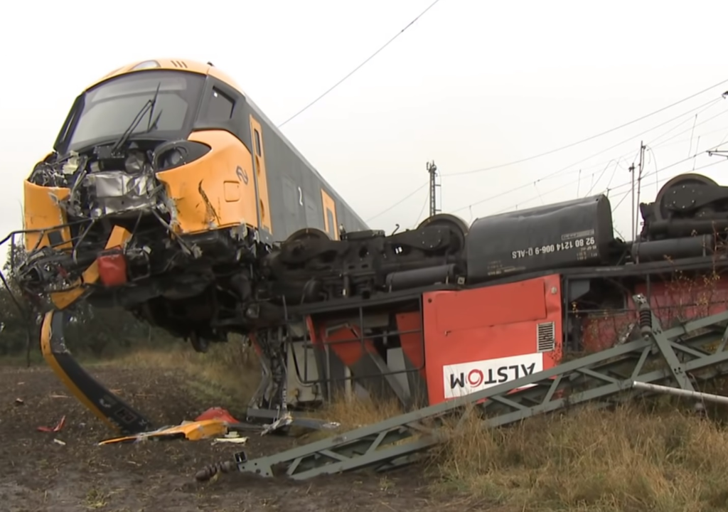 Photo of a derailed ICNG train, with the cab car partially on top of the locomotive that was pulling it. The locomotive, with an "ALSTOM" sticker on its side, lays upside down.